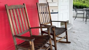 Two wooden rocking chairs on a porch with a red wall and a white door with mailboxes. - DM-A Historic 2BR Apartment (DuBois)