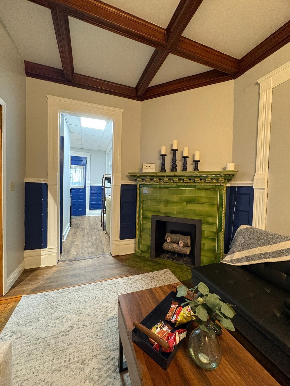 Una sala de estar con chimenea, un sofá, una mesa de centro con aperitivos y un pasillo que conduce a otra habitación.