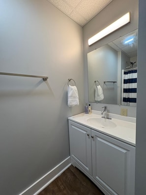 A bathroom with a white sink, two towel rings, a mirror, and a shower curtain.