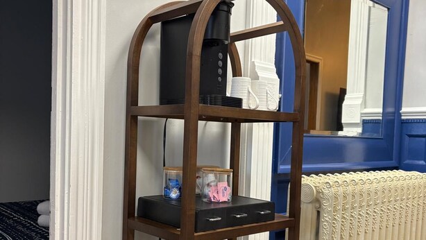 A wooden shelf unit with electronic devices and storage containers. - DM-A Historic 2BR Apartment (DuBois)
