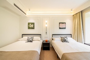 Ein Hotelzimmer mit zwei Betten, einem Nachttisch, einer Wandleuchte und floralen Bildern in Rahmen.