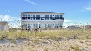 Ein zweistöckiges Gebäude mit einem Balkon im oberen Geschoss, umgeben von Sand und Gras.