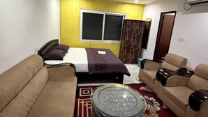 Una habitación con una cama, dos sofás, una mesa de centro redonda, una ventana y un equipo de aire acondicionado.