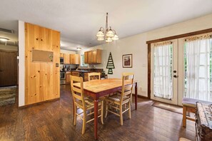 Une cuisine spacieuse avec des meubles en bois, une table à manger et un lustre.