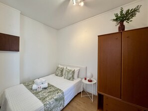 Un dormitori amb llit, una taula de nit, un armari i una planta en test.