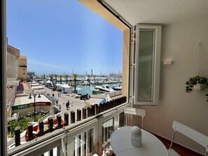 A balcony with a view of a marina, a table with a chair, and a hanging plant. - Vilamoura Marina View 5 by Homing (Loulé)