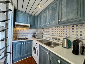 A compact kitchen with a washing machine, a microwave, a sink, and a coffee maker. - VILAMOURA MARINA VIEW 5 by HOMING (Vilamoura)