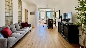 Un salon avec un canapé, une table à manger, des chaises, un téléviseur et une plante.