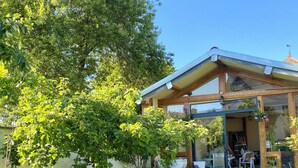Ein Haus mit einer verglasten Veranda, einem Blumentopf und einem strahlend blauen Himmel.