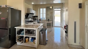 Une cuisine équipée d’un réfrigérateur, d’une cuisinière, d’un évier et d’un petit îlot central avec des rangements.