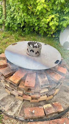 Een ronde vuurkuip met een metalen kom in het midden, omgeven door een vuurvaste ring van bakstenen.