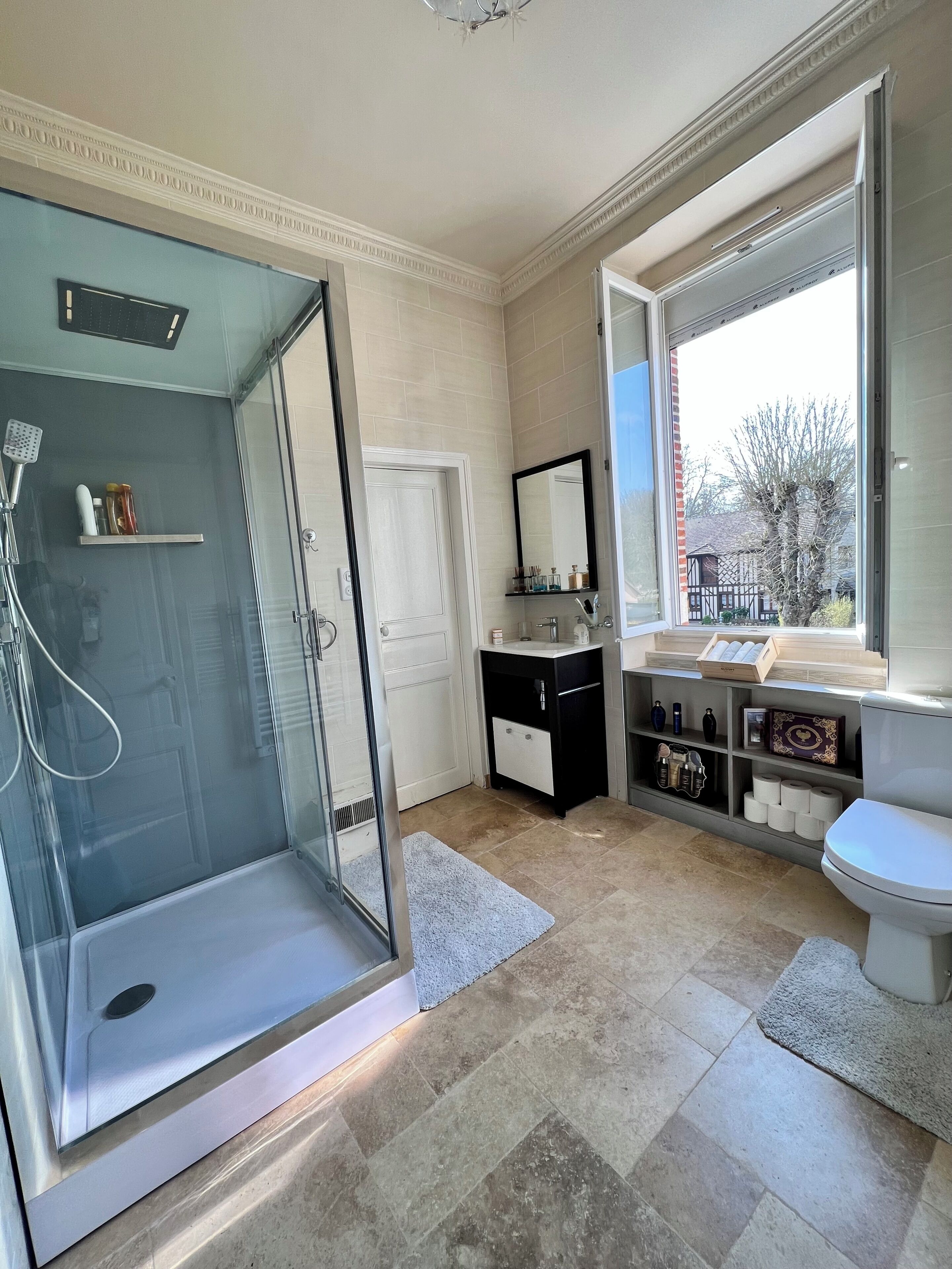 Une salle de bain moderne avec une douche à parois de verre, un meuble-lavabo avec un miroir et des toilettes.