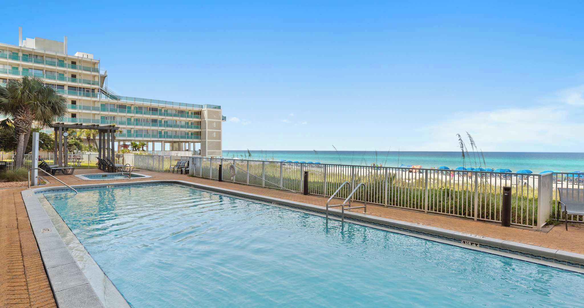 Una piscina con vista a la playa y un edificio de hotel al fondo.