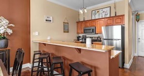Eine Küche mit Holzausstattung, einem Edelstahlkühlschrank, einer Mikrowelle und einer Bar mit Hockern.