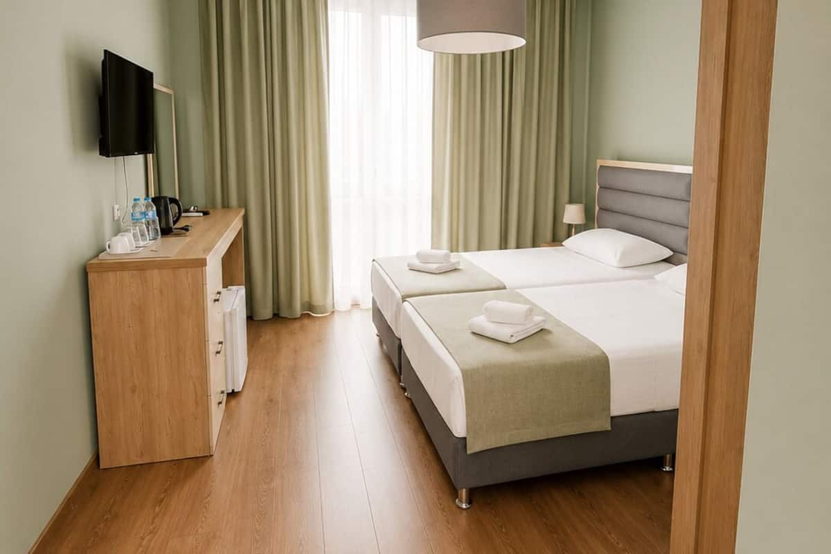 Une chambre d’hôtel équipée d’un lit, d’une table de chevet, d’une télévision et offrant une vue sur l’extérieur.