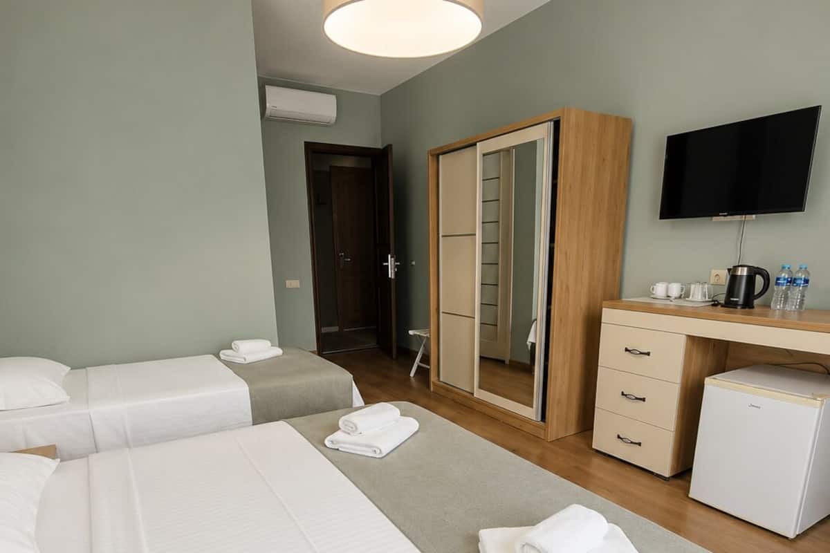 Une chambre d’hôtel avec deux lits, un bureau, une armoire, une télévision et une machine à café.