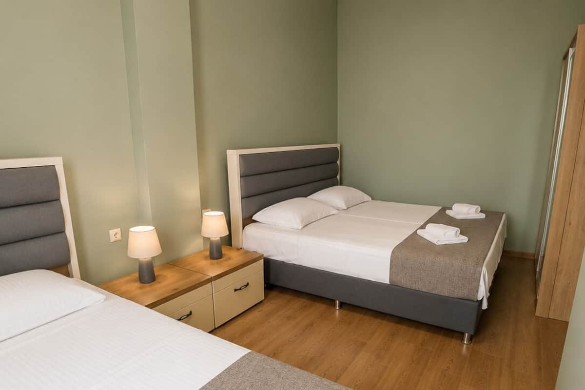 Une chambre d’hôtel avec deux lits, une table de chevet avec une lampe, un plancher en bois et une armoire.