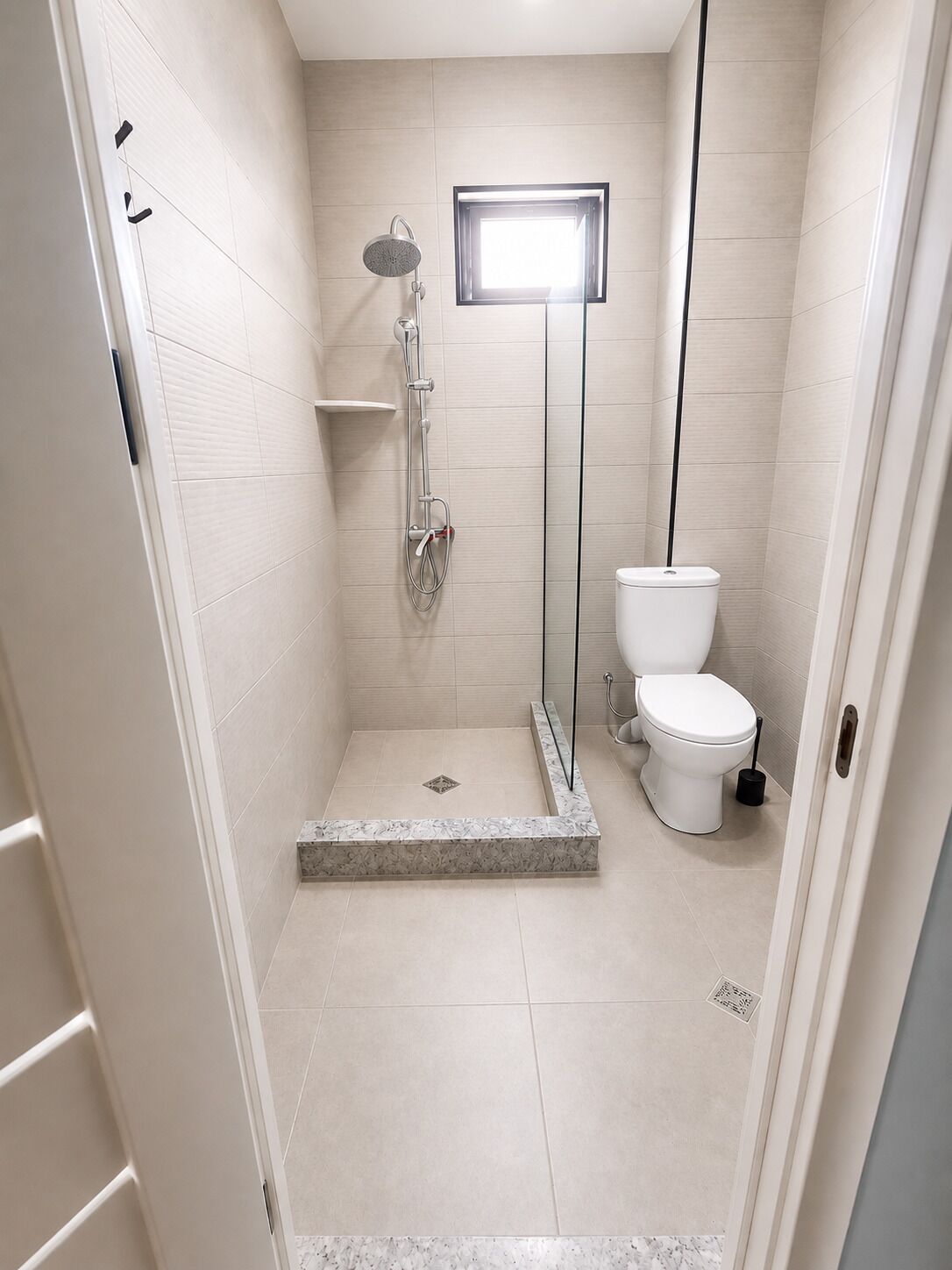 A bathroom with a shower, toilet, and a small window.