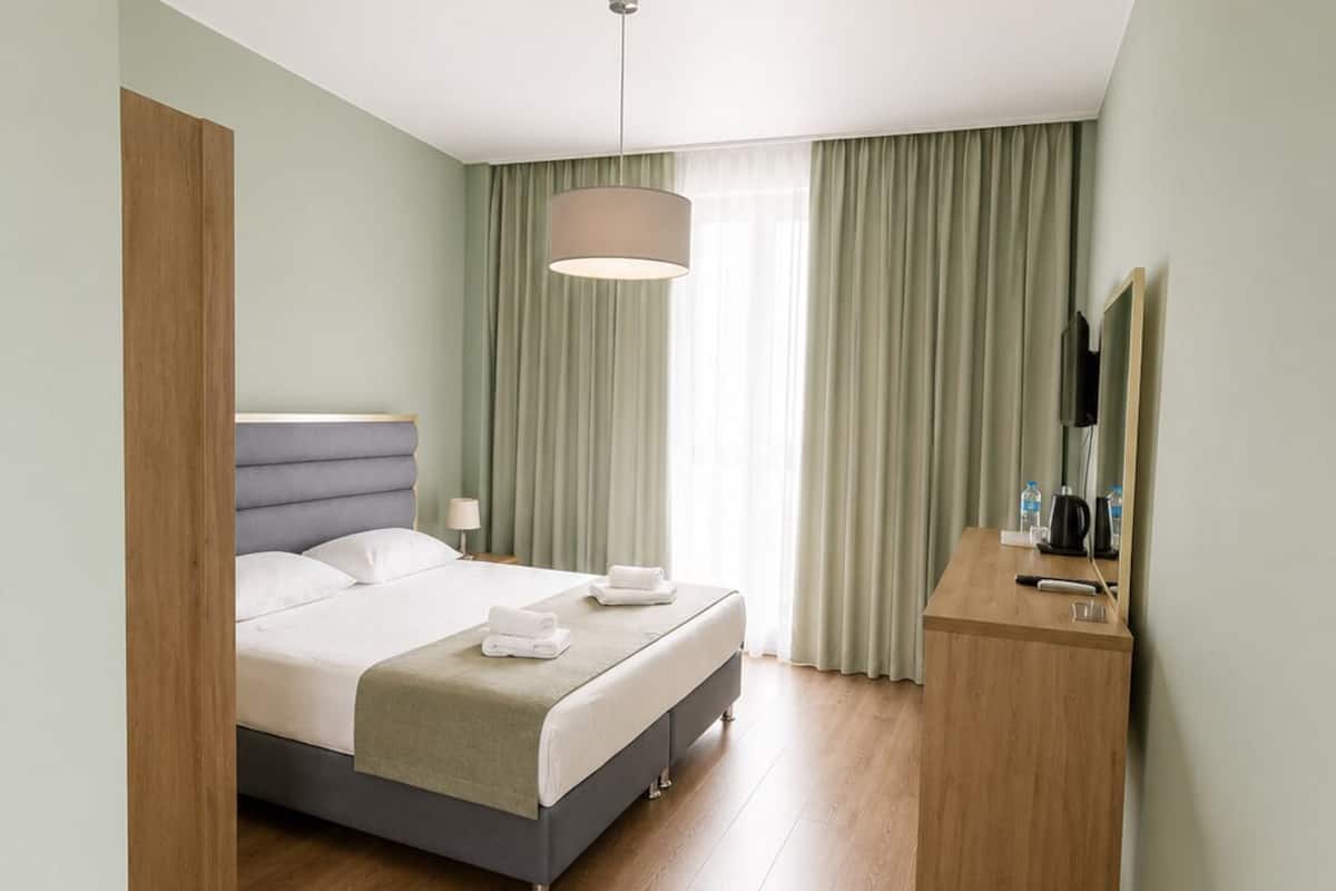 Une chambre d’hôtel moderne, équipée d’un lit, d’une table de chevet et d’un miroir.