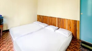 Ein Zimmer mit zwei Betten, einem Holz-Kopfende, einer blauen Tür und einem gemusterten Boden.