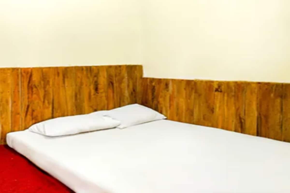 Una cama individual con ropa de cama blanca en una habitación con paneles de madera en las paredes.