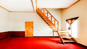 Ein Zimmer mit rotem Teppich, einer Holztreppe und einer Tür.