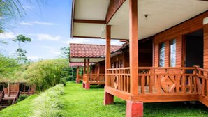 Eine Holzhütte mit Veranda, umgeben von üppigem Grün.