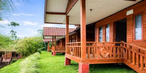 Eine Holzhütte mit Veranda, umgeben von üppigem Grün.