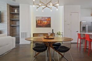 A modern kitchen with a dining area, a large painting, and a built-in wooden shelf. - Sloan's Lake Luxury | Private Rooftop | 30-Day Min (Denver)