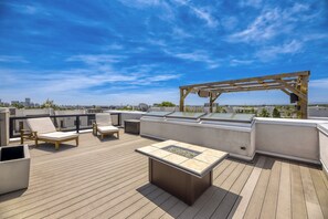 A rooftop terrace with wooden flooring, lounge chairs, a fire pit, and a pergola. - Sloan's Lake Luxury | Private Rooftop | 30-Day Min (Denver)