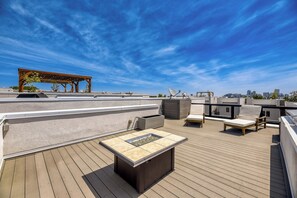 A rooftop deck with a wooden pergola, a built-in fire pit, and outdoor seating. - Sloan's Lake Luxury | Private Rooftop | 30-Day Min (Denver)