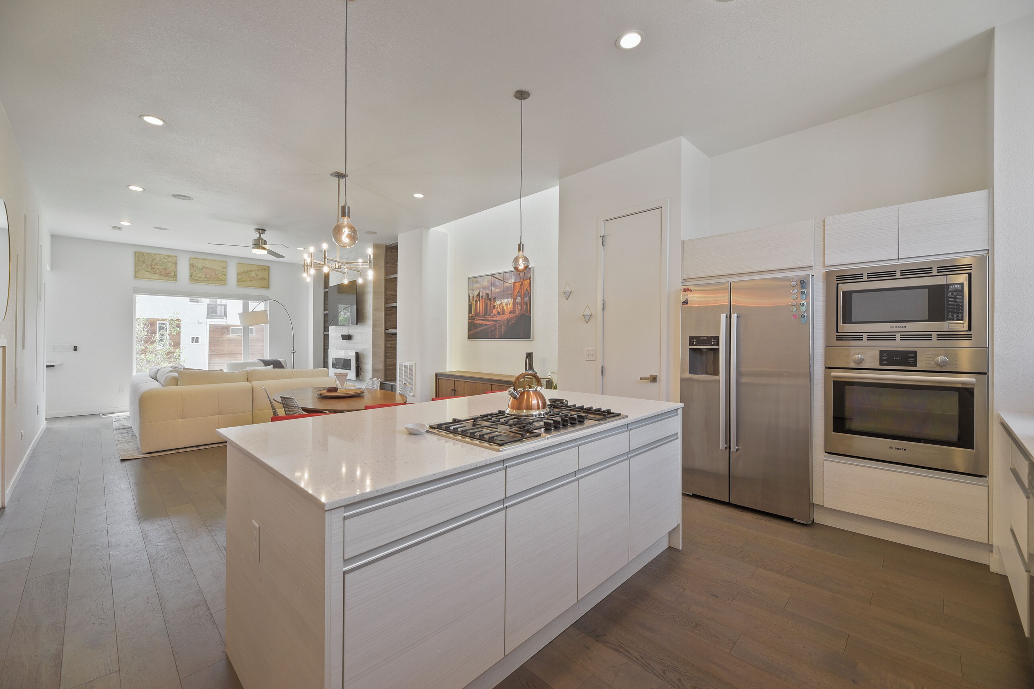 A modern kitchen with a central island, stainless steel appliances, and pendant lighting.