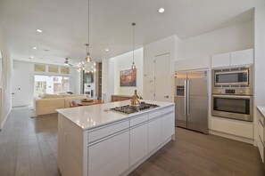A modern kitchen with a central island, stainless steel appliances, and pendant lighting. - Sloan's Lake Luxury | Private Rooftop | 30-Day Min (Denver)