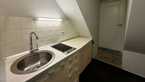 A kitchen with a stainless steel sink, a built-in oven, and a light fixture above the countertop. - Mini-Teater Suites - Apartment 6 - sleeps 5 guests  in 2 bedrooms (Ljubljana)