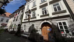 A traditional European building with multiple windows, a wooden door, and a cobblestone street. - Mini-Teater Suites - Apartment 6 - sleeps 5 guests  in 2 bedrooms (Ljubljana)