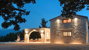 A stone building with a large arched entrance and a second-floor window. - Orientem Villa Heated Pool (Nippos)