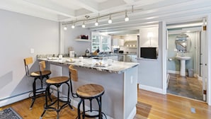 Una cucina moderna con isola centrale, sgabelli da bar e zona pranzo.