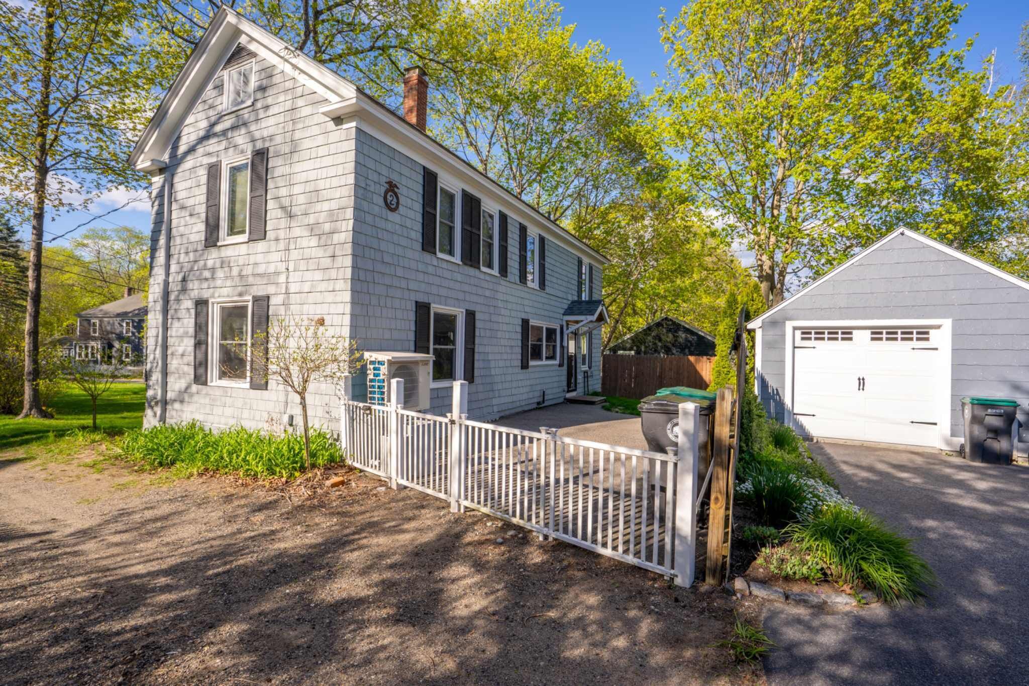 A two-story house with a white exterior, a front porch, and a garage.