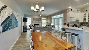 A spacious kitchen with a wooden dining table, white bar stools, and a built-in island with a microwave. - Life's A Beach | Private Pool, Pet Friendly, Close to Beach (Tybee Island)
