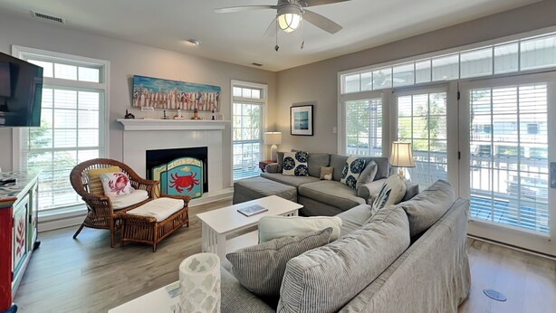 A living room with a fireplace, a sofa, a television, and a ceiling fan. - Life's A Beach | Private Pool, Pet Friendly, Close to Beach (Tybee Island)