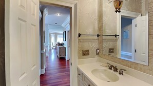 A bathroom with a large mirror, a sink, and a towel rack. - Tybee Nights | Great Views, Steps From Sand, Elevator (Tybee Island)