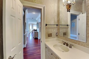 A bathroom with a large mirror, a sink, and a towel rack. - Tybee Nights | Great Views, Steps From Sand, Elevator (Tybee Island)