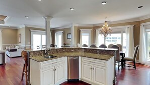 A spacious kitchen with a central island, white cabinetry, and a chandelier. - Tybee Nights | Great Views, Steps From Sand, Elevator (Tybee Island)