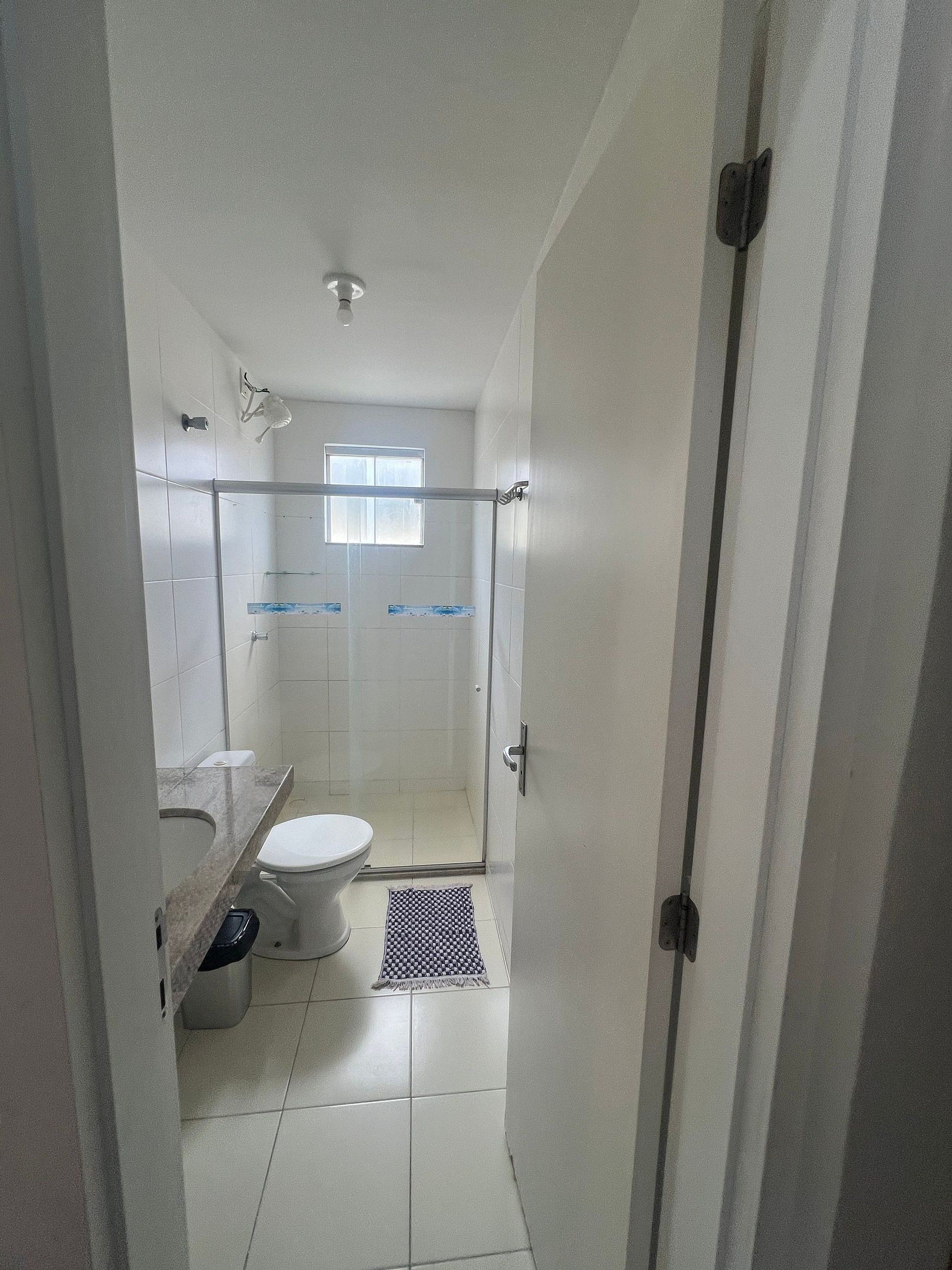 A bathroom with a toilet, a shower area, and a sink.