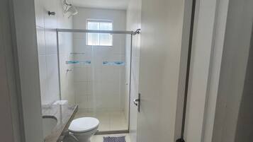 A bathroom with a toilet, a shower area, and a sink.