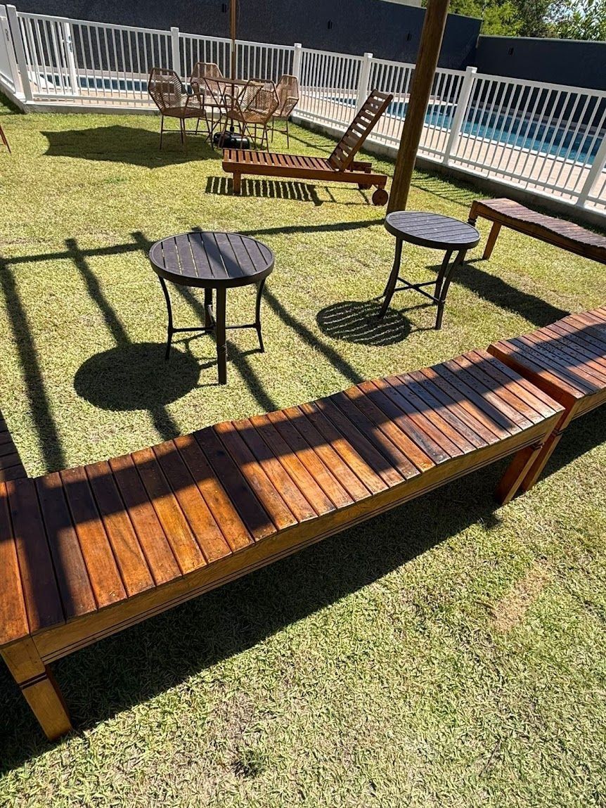 Un giardino con un patio in legno, una piscina e mobili da esterno.
