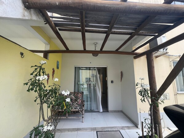 Un patio techado con un banco y plantas en macetas.