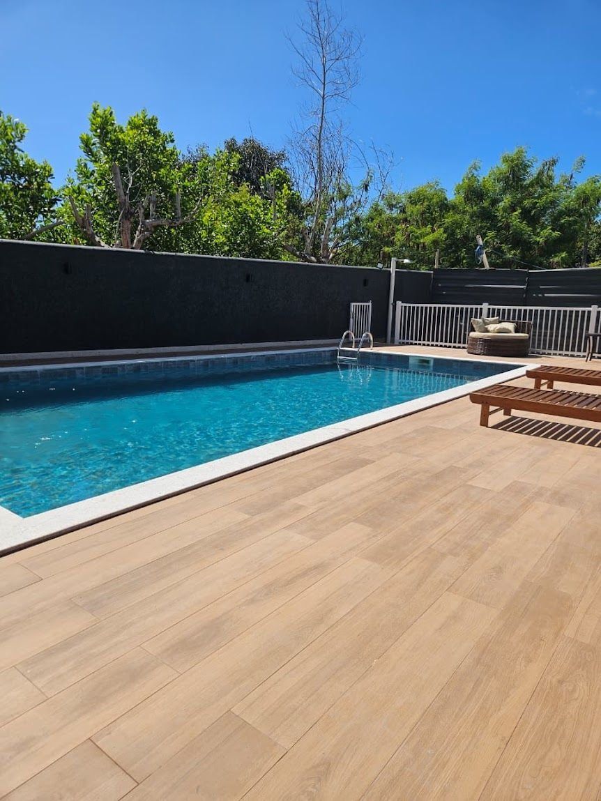 A swimming pool with a wooden deck and a white railing.