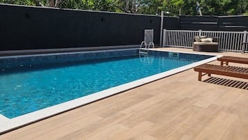 A swimming pool with a wooden deck and a white railing.