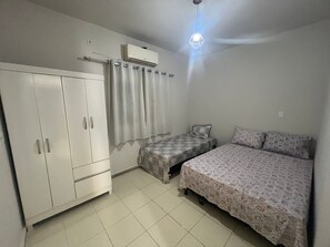 Un dormitorio con cama, armario, cortina y aire acondicionado.